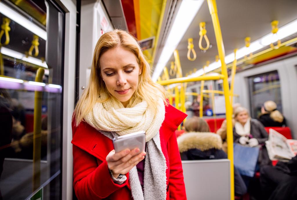 Kvinnelig passasjer på t-banen ser på en mobil