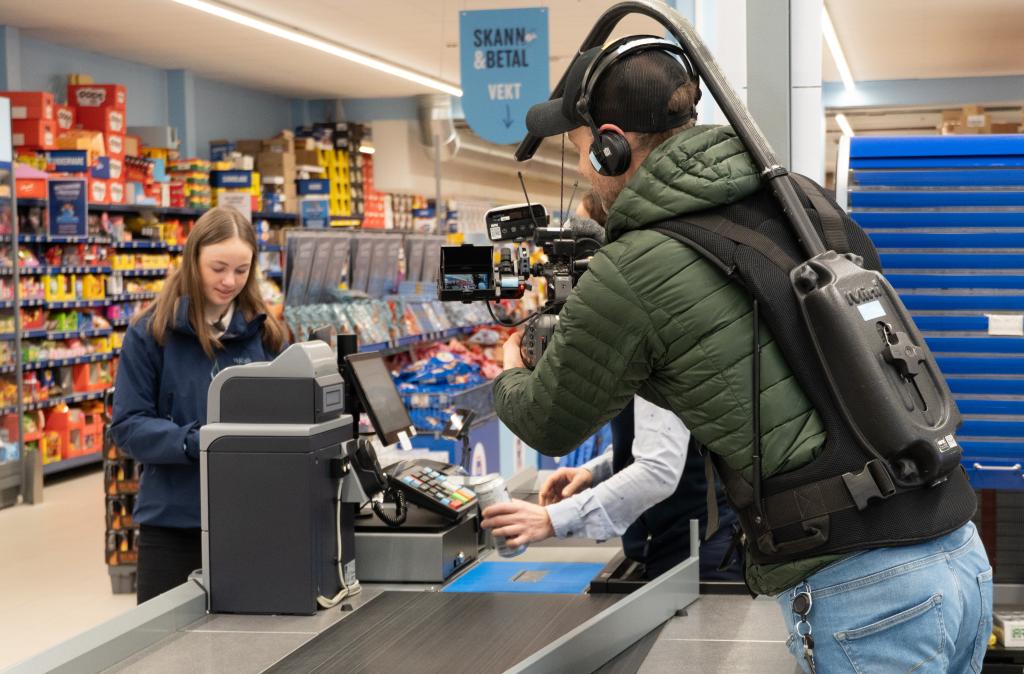 Ingrid bruker den digitale lommeboken ved kassen i butikken til aldersverifisering. NRK filmer seansen. 